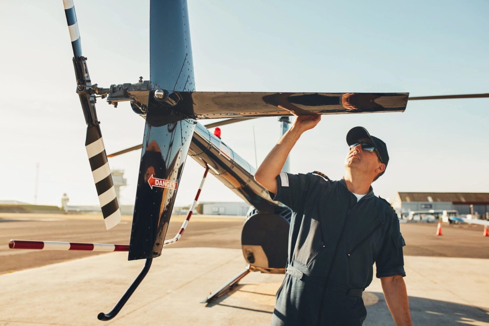 A man holding up a helicopter on top of an airport runway.